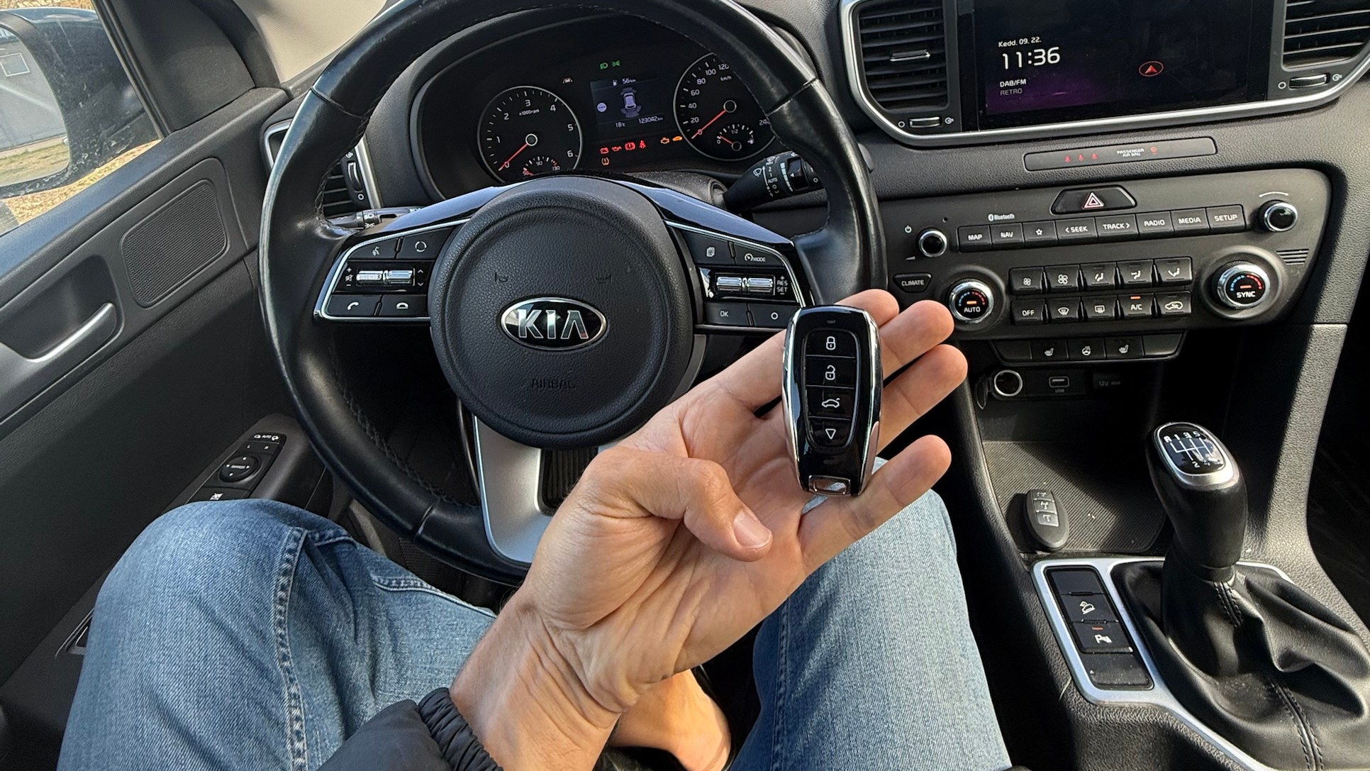 Az elkészült keyless autókulcs a Kia Sportage utasterében, bekapcsolt műszerfal mellett