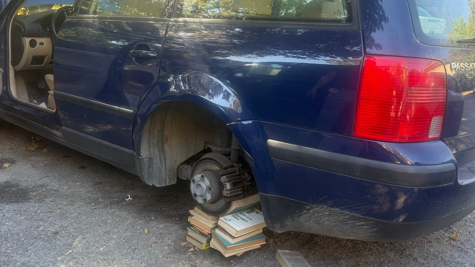 Volkswagen Passat leszerelt hátsó kerékkel, az autó egy halom könyvre felpolcolva