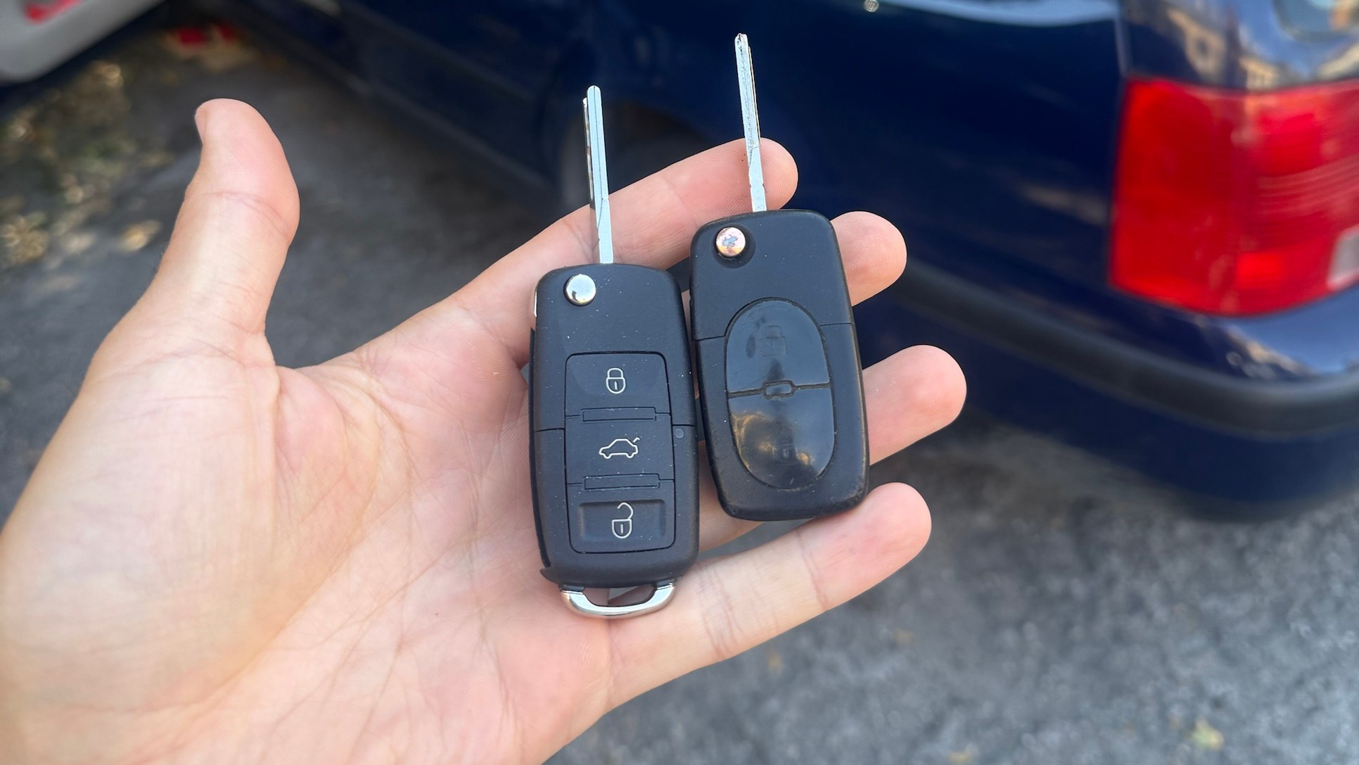 Az elkészült új Volkswagen autókulcs a régi mellett, a háttérben a felpolcolt Passat