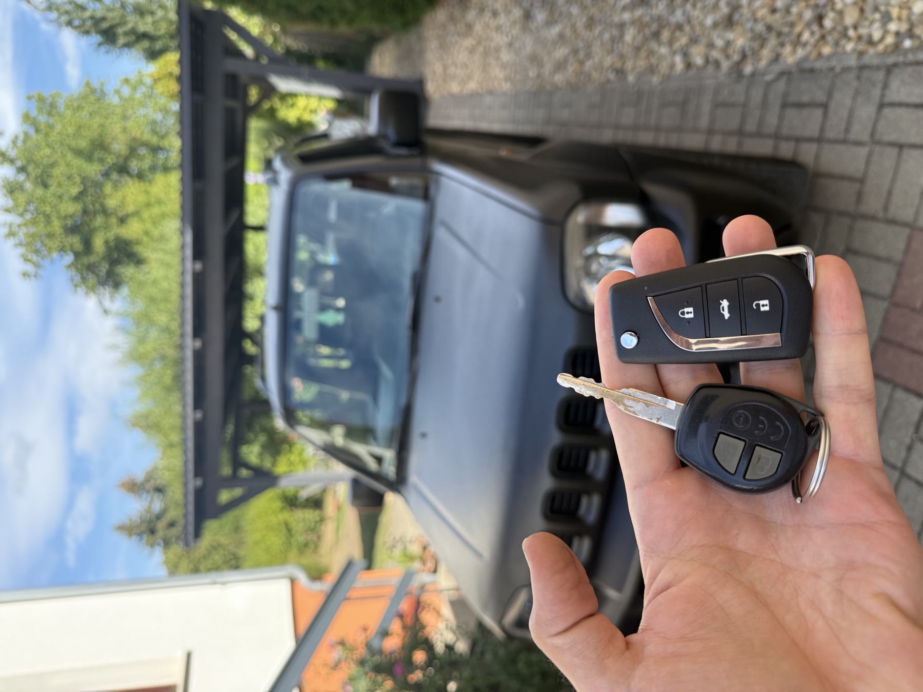 Elkészült Suzuki bicskakulcs az eredeti kulcs mellett, a háttérben a fekete Suzuki Jimny