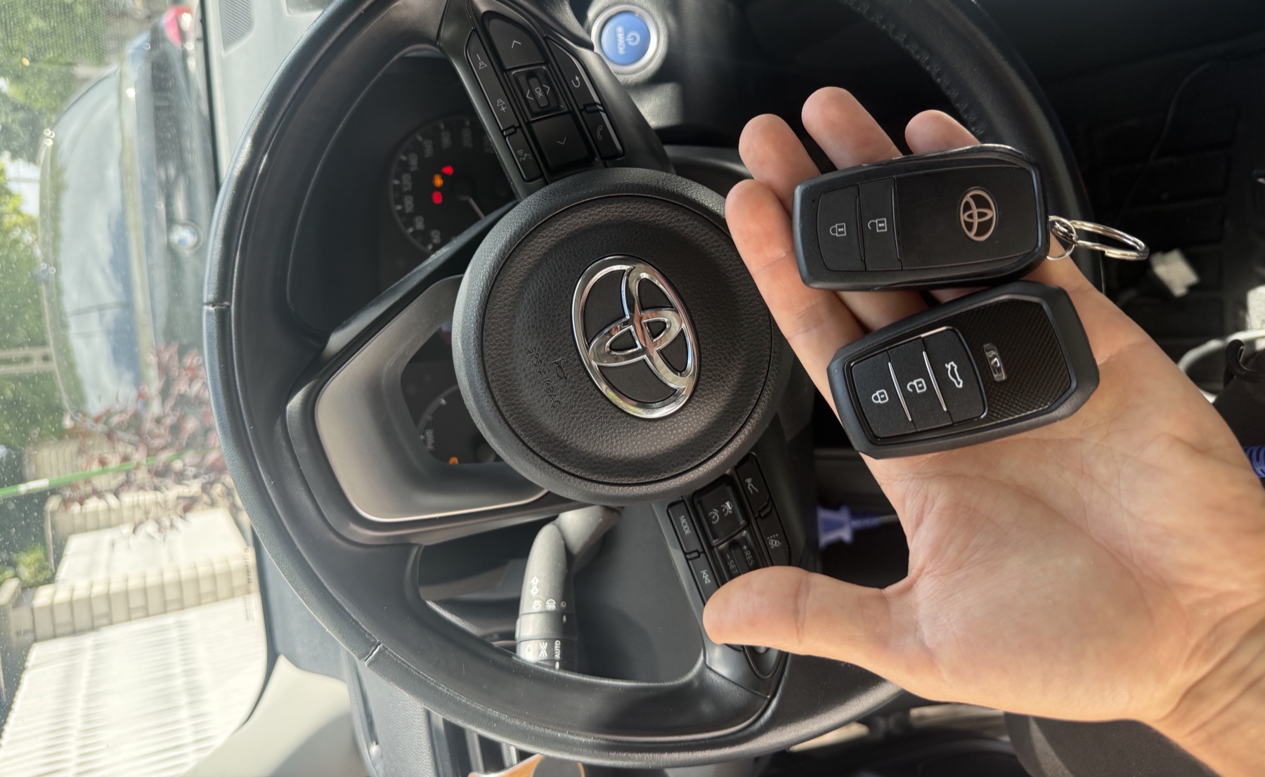 Két elkészült Toyota kulcs kézben, a háttérben a jármű kormánya